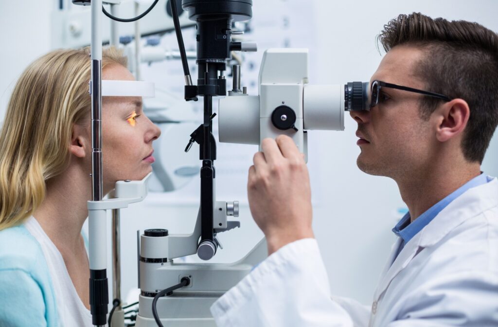 A male optometrist performing a slit lamp exam on a female patient during an eye exam.
