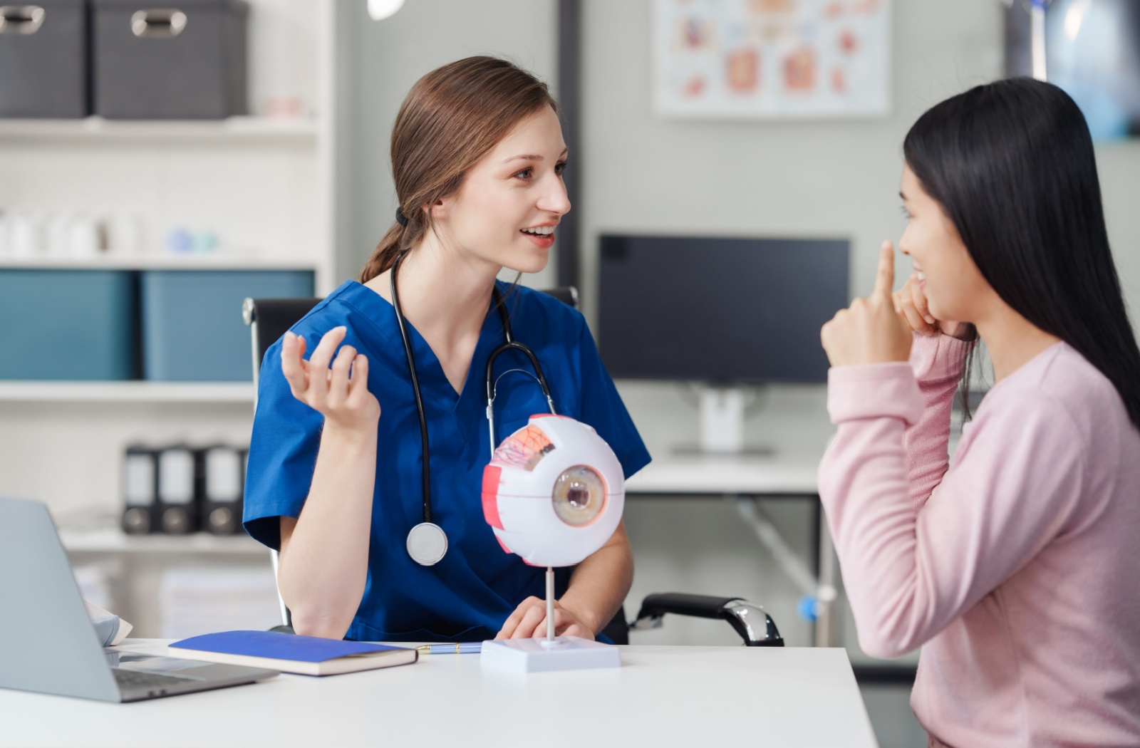 An optometrist explains how light enters the eye to a patient during their routine eye exam.