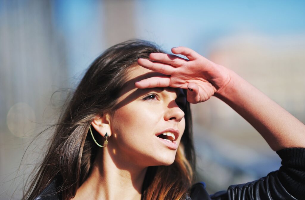 A person tries to protect their eyes from the sun using their hand.
